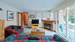A living room with a sofa, television, fireplace, and large windows. - Whistler - The Lagoons 72 (Whistler)
