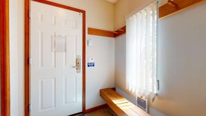 A hallway with a white door, a bench, and a window with blinds. - Whistler - The Lagoons 72 (Whistler)