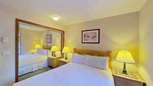 A hotel room with a large bed, two bedside tables, a mirror, a framed picture on the wall, and a ceiling light. - Whistler - The Lagoons 72 (Whistler)