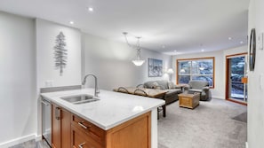A modern kitchen with a large island, wooden cabinets, and a built-in sink. - Whistler - The Aspens 129 (Whistler)