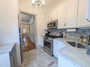 A kitchen with white cabinets, a stainless steel microwave, a gas stove, and a sink. - 4BR WCM - Linens Included, Pet Friendly, Beach Box (West Cape May)
