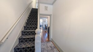 Een trap met een patroonrijk tapijt en een witte balustrade die leidt naar een gang met een bordje 'RELAX'.