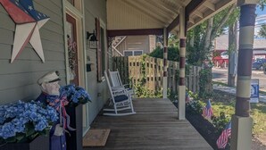 Een veranda met een houten vloer, een schommelstoel en Amerikaanse vlaggen.