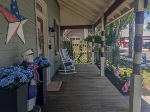 A porch with a wooden floor, a rocking chair, and a statue of a sailor. - NEW 4BR WCM - Linens Included, Pet Friendly, Beach Box (West Cape May)