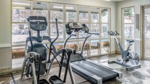Ett gym med konditionsutrustning, inklusive löpband, crosstrainer och motionscykel, med stora fönster som ger utsikt över omgivningen.