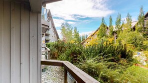 A balcony with a view of a forested area and a building with a sloped roof. - Whistler - The Aspens 262 (Whistler)