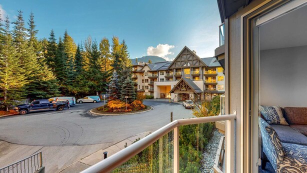 Ein Hotel mit einem zentralen Innenhof, umgeben von hohen Bäumen und einem Berg im Hintergrund.