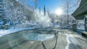 A hot tub surrounded by snow-covered trees and a stone building. - Whistler - The Aspens 263 (Whistler)