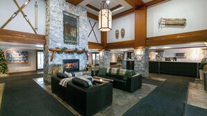 A spacious lobby with a stone fireplace, a reception desk, and a Christmas tree. - Whistler - The Aspens 263 (Whistler)