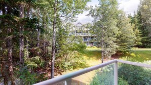 Edificio residencial rodeado de un bosque frondoso, con barandilla de balcón visible.