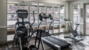 Una palestra con diverse attrezzature per esercizi, ampie finestre e vista su una zona esterna innevata.