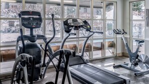A gym with cardio machines, a treadmill, and large windows offering a view of the outside. - Whistler - The Aspens 329 (Whistler)