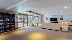 Eine Lobby mit Bücherregal, Sitzecke und Fernseher.
