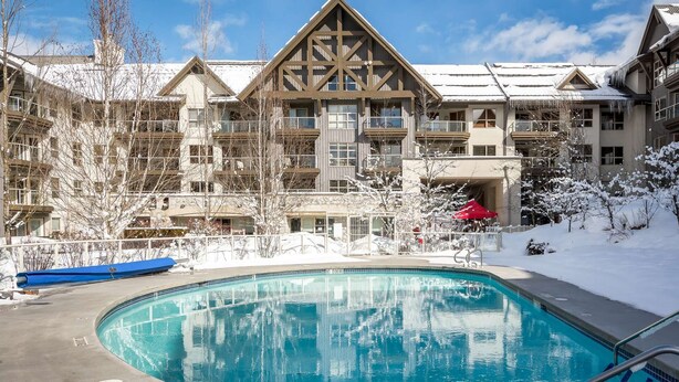 Een resort met een zwembad, meerdere gebouwen met balkons en een besneeuwde omgeving.
