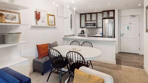Una cocina moderna con una isla central, armarios blancos y electrodomésticos de acero inoxidable.
