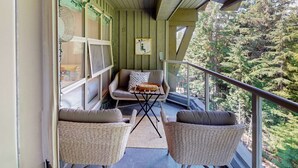 Un balcon agrémenté de meubles en osier, d’une petite table et offrant une vue sur une forêt dense.