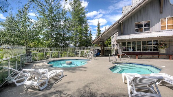 A pool area with two pools, lounge chairs, and a building with large windows. - Whistler - The Aspens 421 (Whistler)