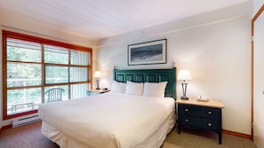 A hotel room with a large bed, two bedside tables, a window with blinds, and a painting on the wall. - Whistler - The Aspens 421 (Whistler)