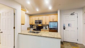 Una cocina moderna con encimeras de granito, electrodomésticos de acero inoxidable y armarios de madera.