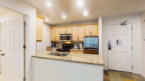 Eine moderne Küche mit Granit Arbeitsplatten, Edelstahlgeräten und Holzschränken.