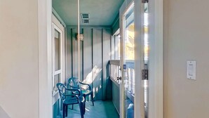 Un couloir étroit avec un mur bleu, une fenêtre et une porte dotée d’un interrupteur.