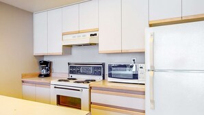 Eine kleine Küche mit Herd, Mikrowelle und Kühlschrank.