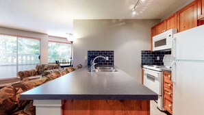 Una cocina moderna con una isla grande, armarios de madera, un lavamanos de acero inoxidable y un horno empotrado.
