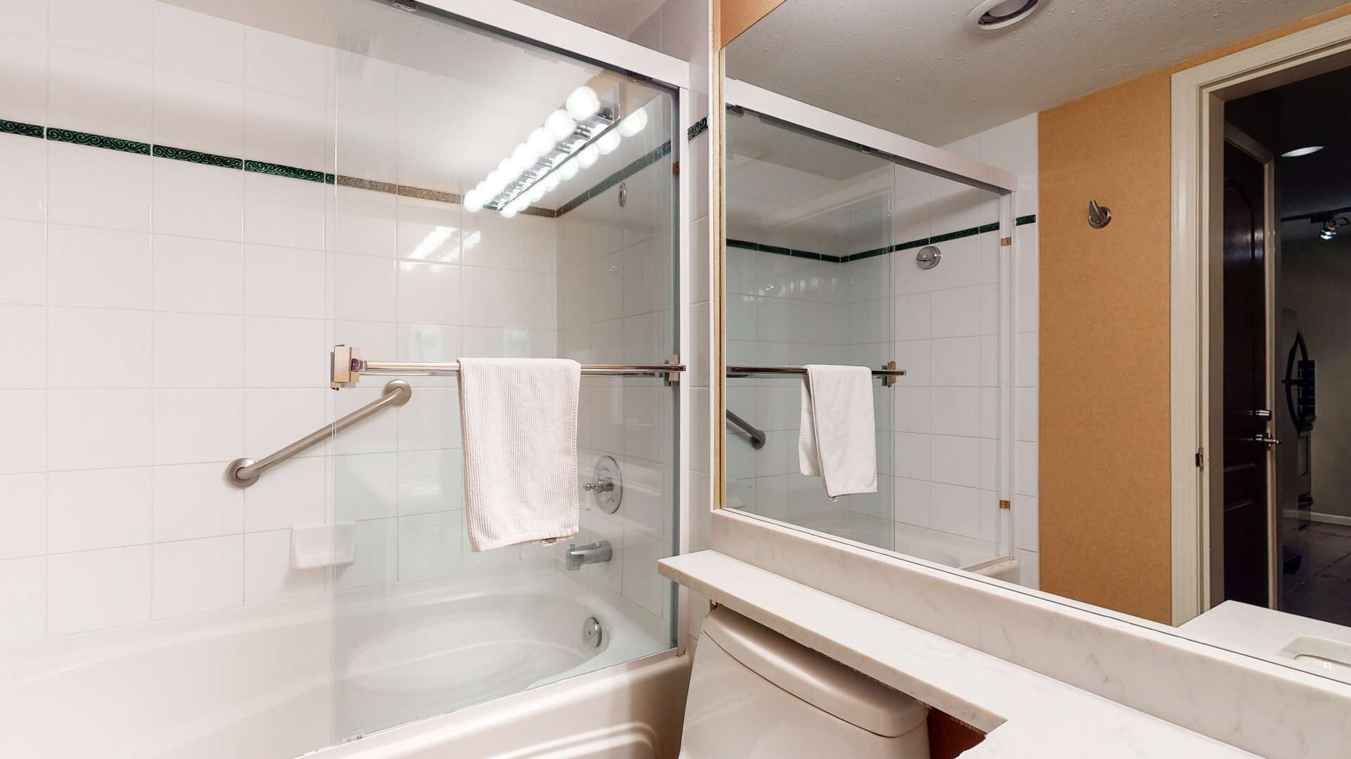 A modern bathroom with a glass-enclosed shower, a bathtub, and a vanity with a mirror.
