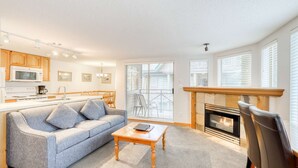 Una sala de estar moderna con sofá, mesa de centro, chimenea y zona de cocina.
