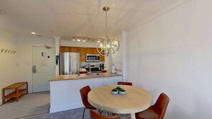 Una cucina moderna con isola centrale, elettrodomestici in acciaio inossidabile e un lampadario particolare.