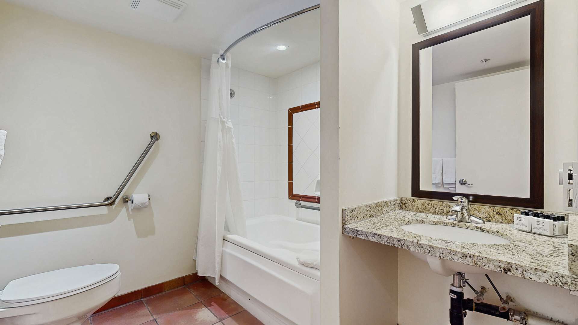 A bathroom with a toilet, a shower with a grab bar, a bathtub, and a sink with a mirror.