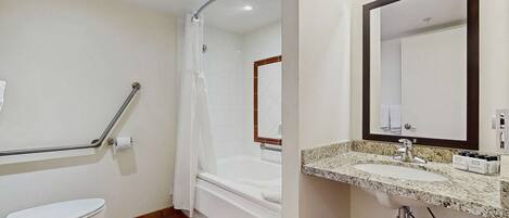 A bathroom with a toilet, a shower with a grab bar, a bathtub, and a sink with a mirror.