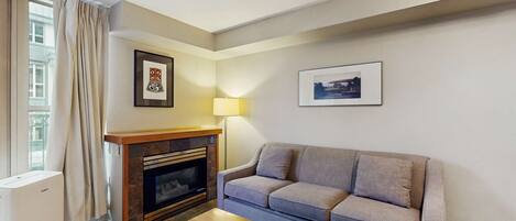 A living room with a fireplace, a sofa, and two framed pictures on the wall.