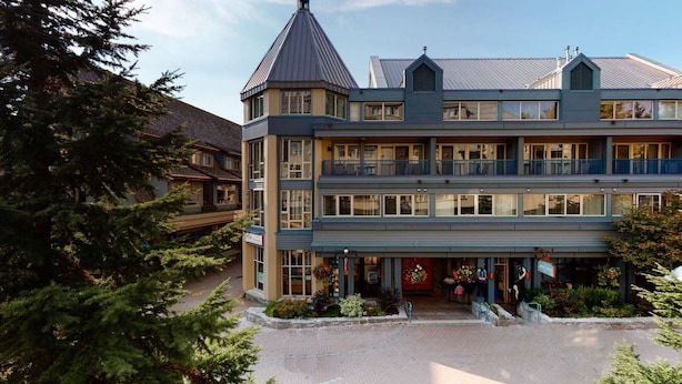 Un hotel de varios pisos con una torre destacada, balcones y un jardín bien cuidado.