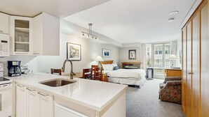 Habitación de hotel con kitchenette, cama, escritorio y balcón con vistas.
