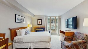 Una habitación de hotel con cama, escritorio, silla, televisión y ventana.