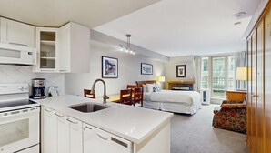 Habitación de hotel con kitchenette, cama, comedor y vistas a la ciudad.