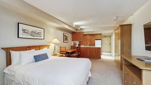 Een hotelkamer met een bed, een bureau, een stoel, een kitchenette en een kledingkast.