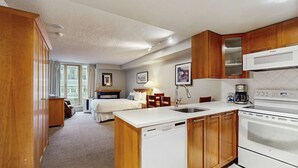 Een hotelkamer met een kitchenette, een bed, een bureau en een raam.