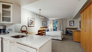 Ein kompaktes Hotelzimmer mit Küchenzeile, einem Bett, einem Schreibtisch und einem Kamin.