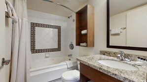Een badkamer met douche, bad, toilet, wastafel en spiegel.