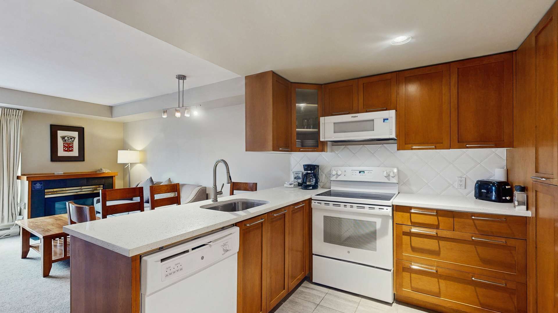 Una cocina compacta con armarios de madera, un microondas integrado, una estufa y un lavavajillas.