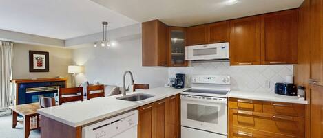 Una cocina compacta con armarios de madera, un microondas integrado, una estufa y un lavavajillas.