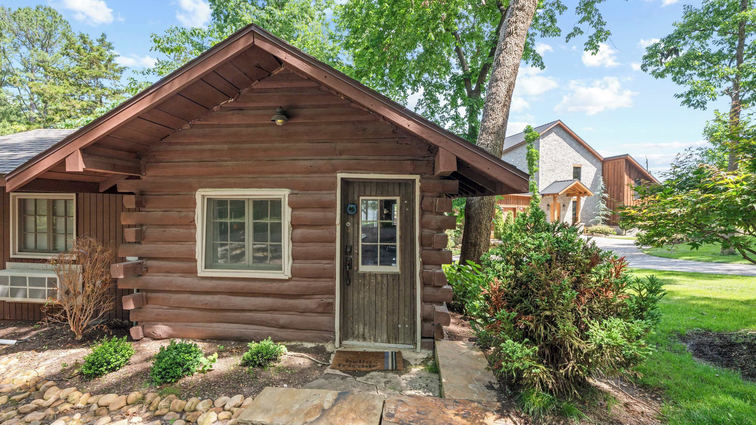 A log cabin with a front door, windows, and a small porch area.