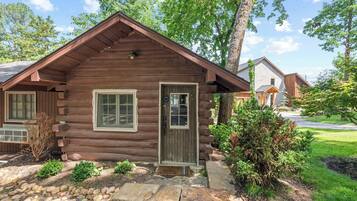 A log cabin with a front door, windows, and a small porch area.