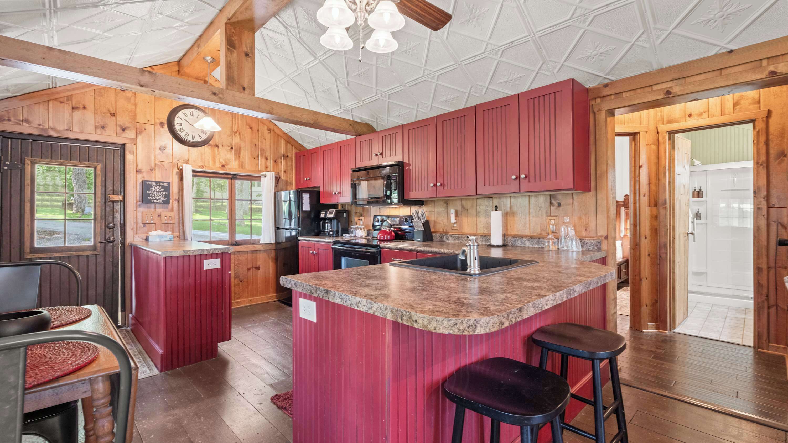A kitchen with wooden walls, a central island, and red cabinets.