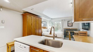 Una cocina compacta con lavavajillas integrado, un lavabo y armarios de madera.