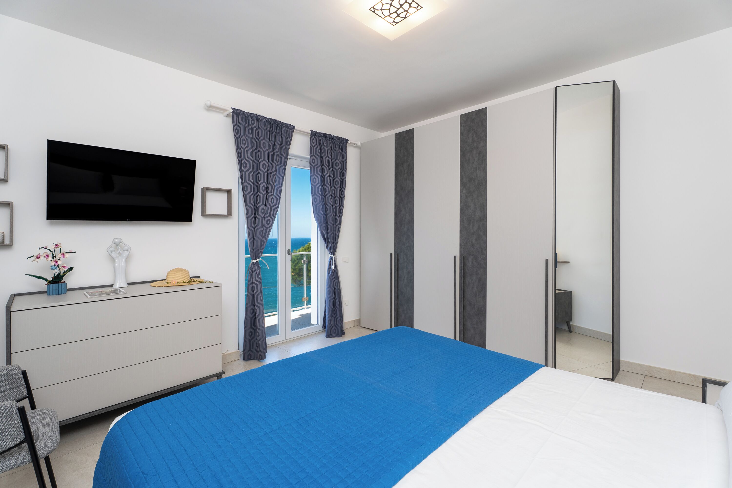 A bedroom with a bed, a TV, a dresser, and a wardrobe.