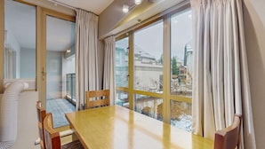 Una habitación con un ventanal grande, una mesa de madera y una silla.
