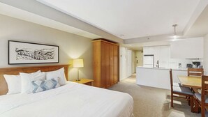 Ein Hotelzimmer mit Bett, Schreibtisch, Stuhl, Kleiderschrank und einer Küchenzeile.